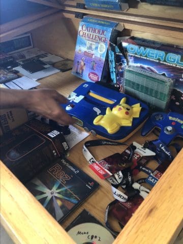 Ken McAllister, Co-Director of LGIRA, reaches into a case displaying original games and gaming systems at LGIRA in Tucson, AZ. 